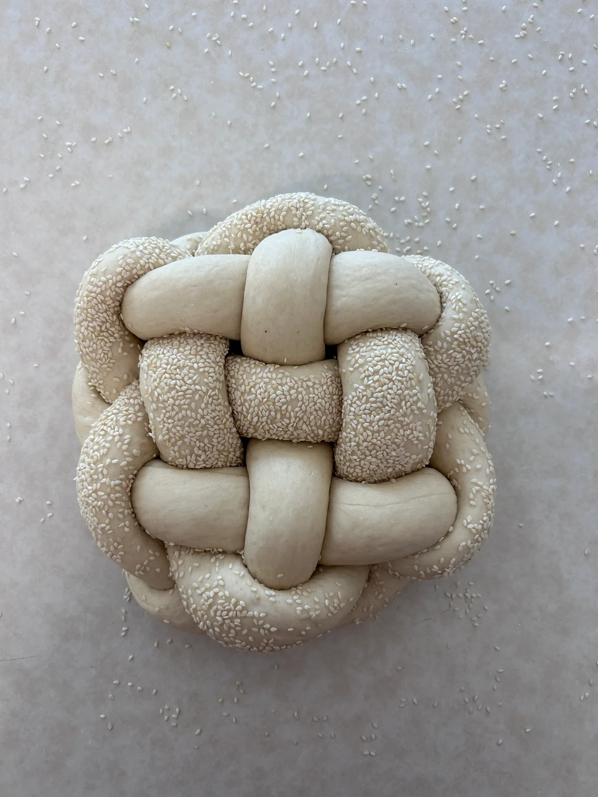 A woven challah dusted with sesame, ready for the oven